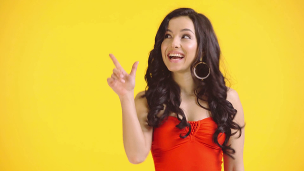 ενθουσιασμένο κορίτσι με μαγιό που δείχνει με τα δάχτυλα απομονωμένα στο κίτρινο - Πλάνα, βίντεο