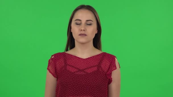 Portrait of tender girl carefully examines something then fearfully covers her face with her hand. Green screen - Imágenes, Vídeo