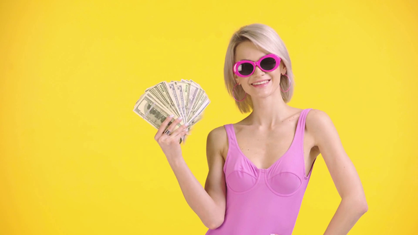 幸せな女の子で水着とサングラスは黄色に隔離されたお金を振って - 映像、動画