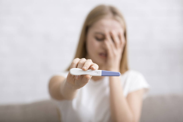 Test di gravidanza positivo tenuto da una giovane donna sconvolta
 - Foto, immagini