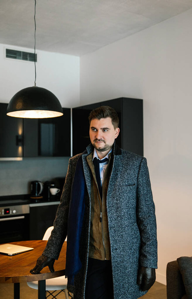 fashionably dressed businessman with a beard - stylish suit, brown shoes, tie, gloves, a man posing in an expensive apartment - Фото, зображення