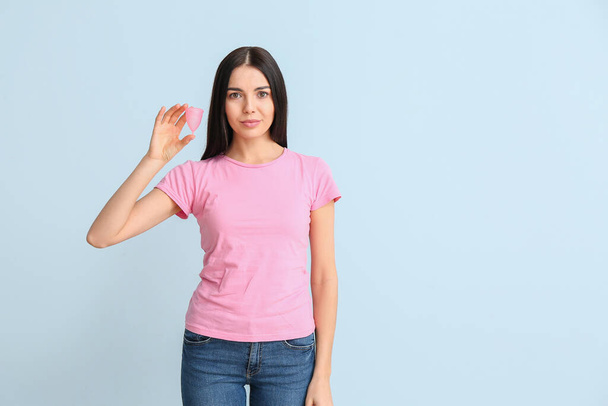 junge Frau mit Menstruationstasse auf farbigem Hintergrund - Foto, Bild