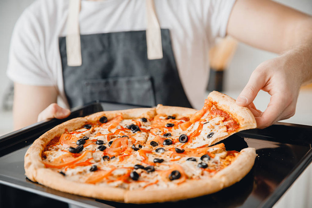 Primer plano italiano caliente margherita pizza fresca con aceitunas en manos del chef masculino
 - Foto, Imagen
