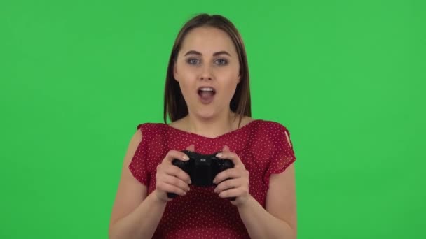 Portrait of tender girl is playing a video game using a wireless controller and rejoicing in victory. Green screen - Filmagem, Vídeo