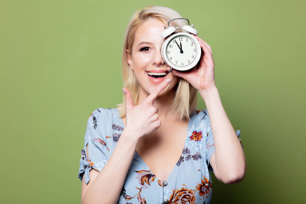 Blonde woman with alarm clock on green background - Zdjęcie, obraz