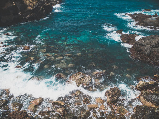 Imagen tonificada de olas marinas turquesas rodando y rompiendo en acantilados y rocas afiladas en la orilla
 - Foto, imagen