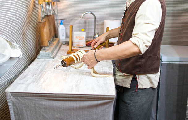 Préparation du Trdelnik traditionnel une sorte de gâteau à la broche fait de pâte roulée enroulée autour d'un bâton, grillé
 - Photo, image