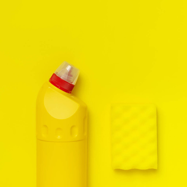 House cleaning concept. Household chemicals, disinfectant, bleach, antibacterial gel, yellow rubber gloves, sponge, rags on yellow background. Flat lay top view copy space. Cleaning accessories - Photo, image