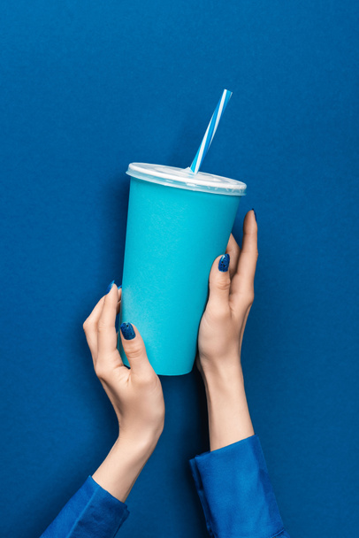cropped view of woman holding paper cup on blue background  - Fotografie, Obrázek