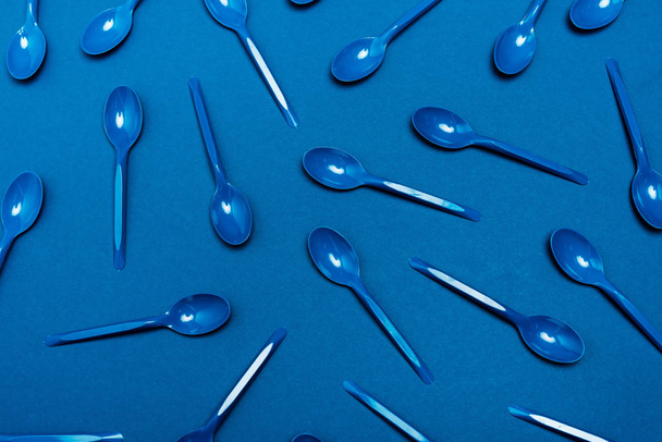 top view of plastic spoons on blue background  - Foto, imagen