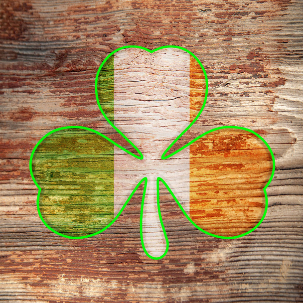 День Святого Патрика. Ирландский флаг цвета трилистник с зеленой границей нарисован на старой, потрепанной деревянной поверхности. Трехлистный клевер
.  - Фото, изображение