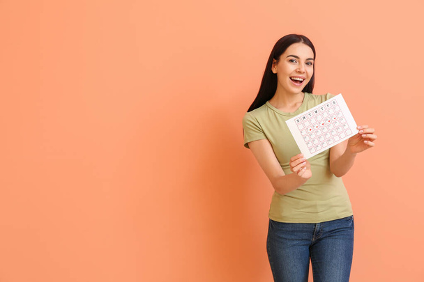Jonge vrouw met menstruele kalender op kleur achtergrond - Foto, afbeelding