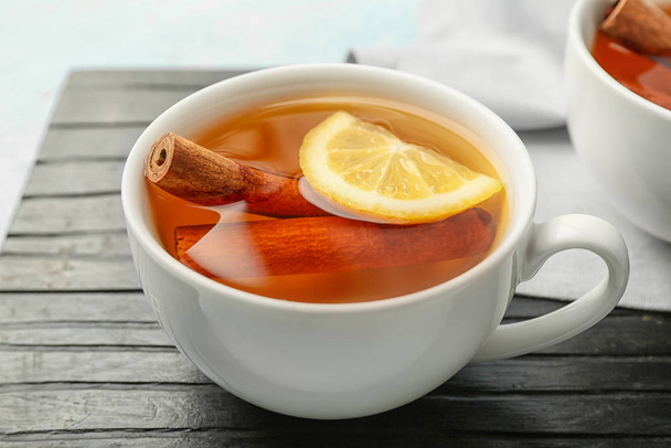 Чашка гарячого чаю з лимоном і корицею на столі
 - Фото, зображення