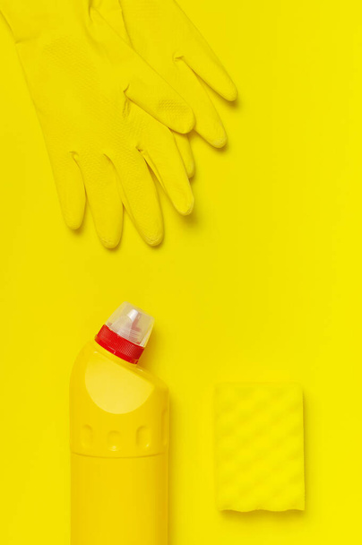 House cleaning concept. Household chemicals, disinfectant, bleach, antibacterial gel, yellow rubber gloves, sponge, rags on yellow background. Flat lay top view copy space. Cleaning accessories - Фото, изображение