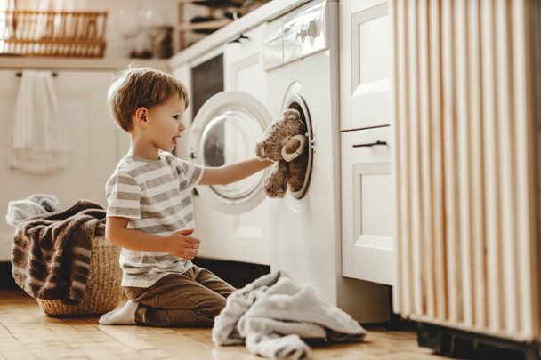 happy  householder child boy in laundry   with washing machin - Foto, afbeelding
