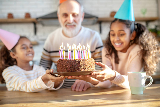 Two dark-skinned girls holding his grandads birthday cake - Foto, immagini