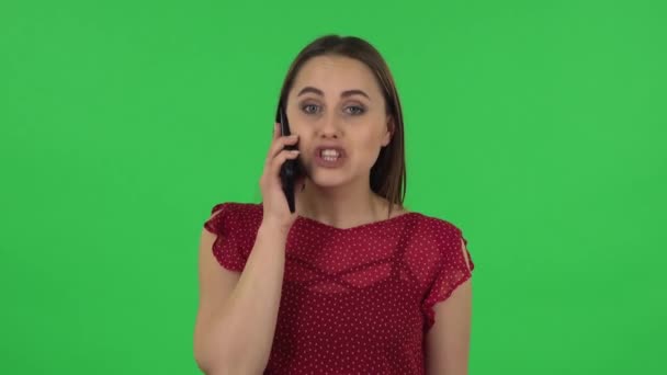 Portrait of tender girl in red dress is talking for mobile and shocked then rejoice. Green screen - Filmagem, Vídeo
