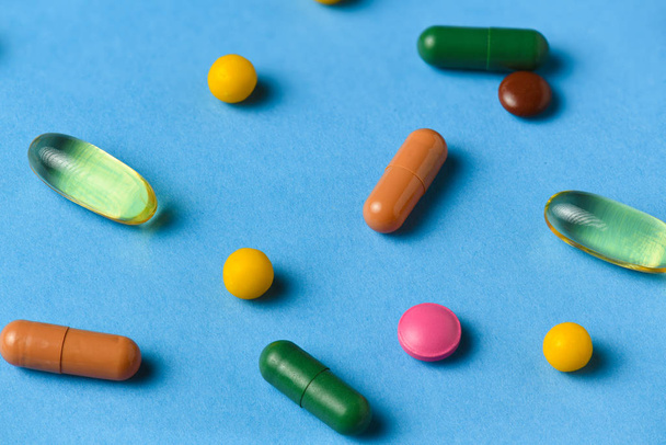 Pillereiden, tablettien, vitamiinien, lääkkeiden, omega 3 kalaöljyn, geelikapseleiden, lääkkeiden ja ravintolisien tausta terveydenhuoltoon sinisellä
 - Valokuva, kuva