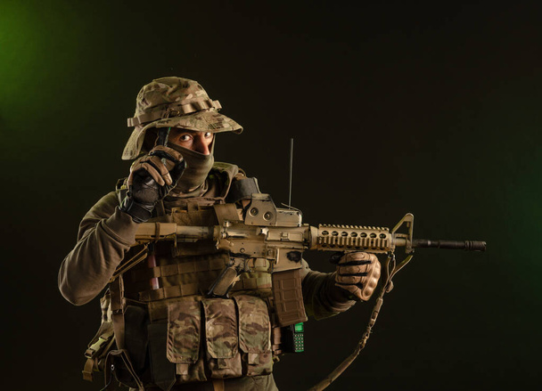 soldier-saboteur in military clothing with weapons on a dark background - Photo, Image