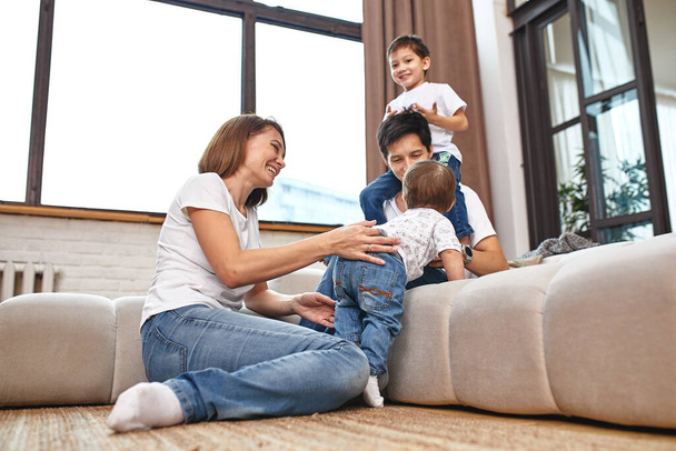 międzynarodowa rodzina w domu na kanapie, przytulić i cieszyć się życiem. Szczęśliwe życie rodzinne - Zdjęcie, obraz
