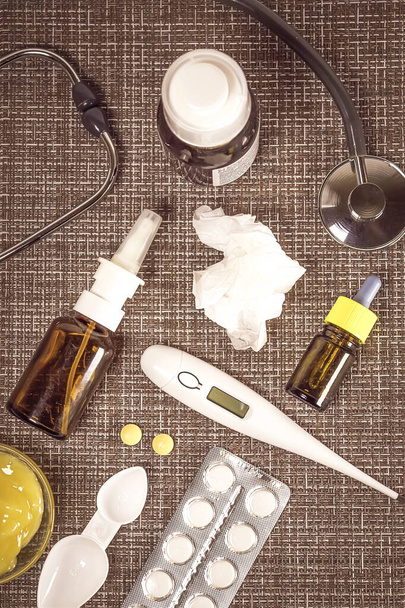 Treatment of colds and flu. Various medications, cold pills, throat spray, nasal drops, and a paper napkin on a brown background. Treatment of influenza. Medicine flat lay. - Photo, Image