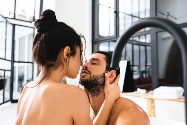 Beautiful naked woman kissing handsome boyfriend in bathtub  - Photo, Image