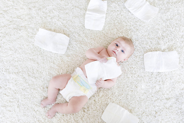 Cute adorable newborn baby of 3 moths with diapers. Hapy tiny little girl or boy looking at the camera. Dry and healthy body and skin for children concept. Baby nursery. - Photo, Image