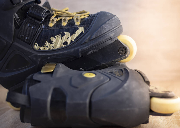 fotografias de patins em linha pretos com cadarços dourados no chão de madeira
 - Foto, Imagem