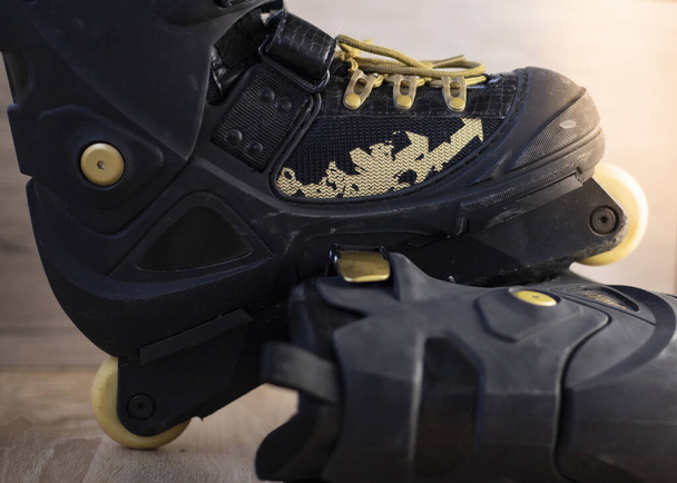 fotografias de patins em linha pretos com cadarços dourados no chão de madeira
 - Foto, Imagem
