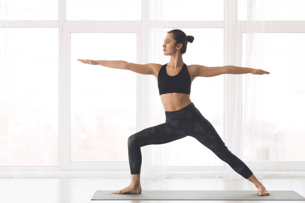 Mujer ejercitando yoga en pose guerrera en casa
 - Foto, imagen