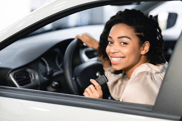 Ευτυχισμένη μαύρη κυρία κάνει τεστ ντράιβ παριστάνοντας κάθεται στο αυτοκίνητο - Φωτογραφία, εικόνα