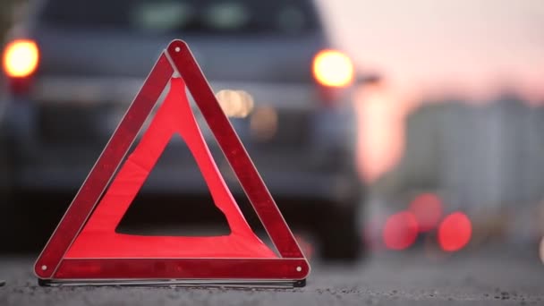 Rode noodstopbord achter kapotte wazige auto met knipperende lichten op de avond stad straat stoeprand. - Video