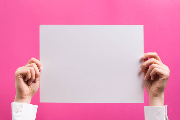 Woman holding blank white A4 paper on bright pink background - Fotografie, Obrázek