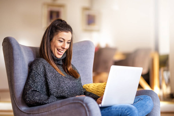 Happ young woman using notebook while working from home  - Φωτογραφία, εικόνα