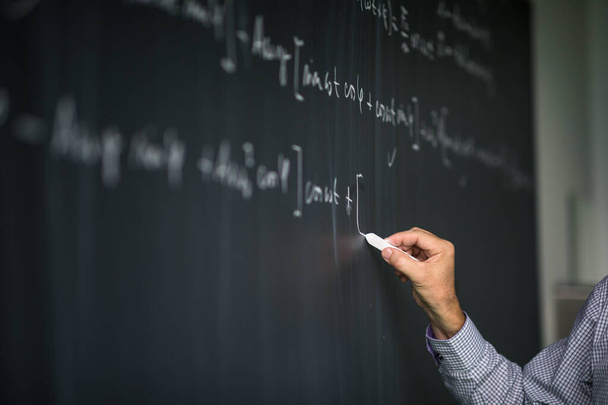 Math teacher by the blackboard during mathclass - Photo, image
