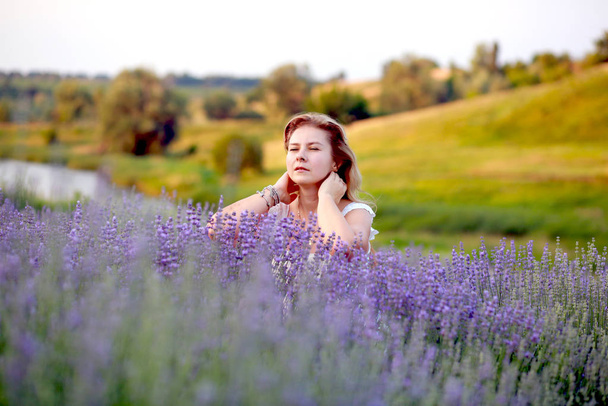 eine junge Frau im weißen Kleid geht durch ein Lavendelfeld - Foto, Bild