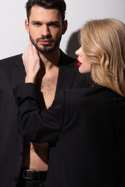 donna attraente con labbra rosse toccando uomo barbuto su bianco
 - Foto, immagini