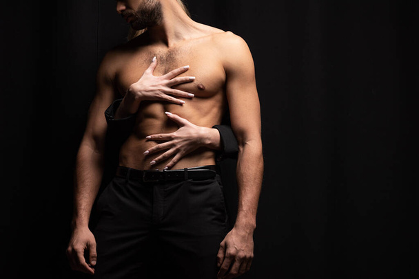cropped view of young woman touching muscular man isolated on black  - Fotografie, Obrázek