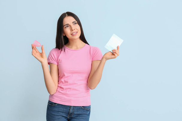 Young woman with menstrual pad and cup on color background - Foto, Imagem