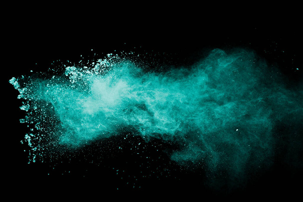 Abstract green dust splattered on black background. Freeze motion of green powder splash. - Photo, Image