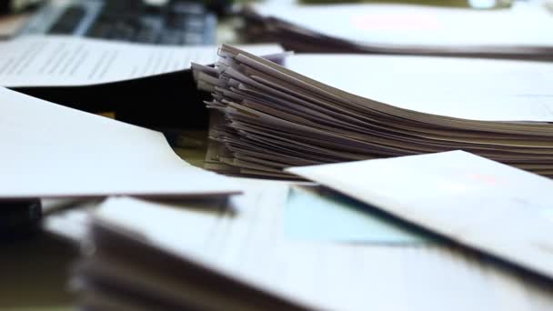 Detailní záběr zásobníku papíru se sešívačkami v mělkém DOF a za zajímavého světla. Staré dokumenty. Spousta práce je odložena. Skutečná kancelářská práce - Záběry, video