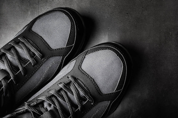 Zwarte sportschoenen close-up. Het concept van comfortabele casual schoenen. Donkere achtergrond, minimalisme, copyspace, bovenaanzicht, flat lay. - Foto, afbeelding
