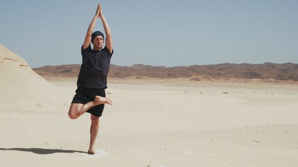 Hezký samec dělá jógu ardha padma vrikshasana na skále v poušti - Fotografie, Obrázek