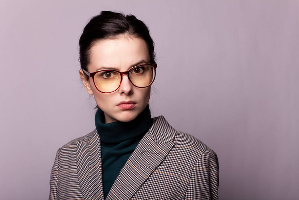 girl in a green turtleneck, jacket, glasses, portrait on a gray background - Photo, Image