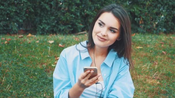 Pretty, adorable girl listens to music using headphones in the park. Close up. Copy space. 4K. - Кадры, видео