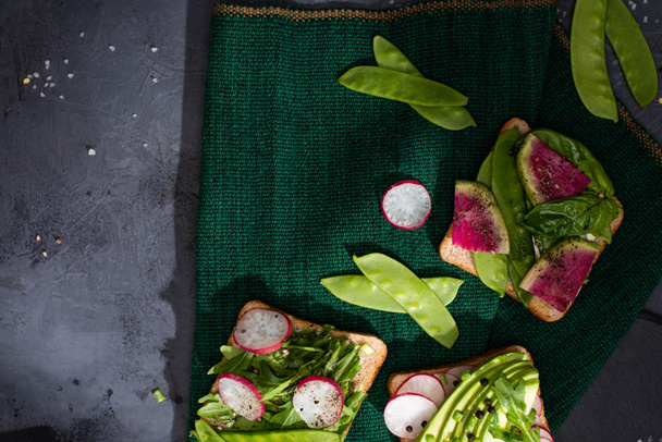 widok z góry wegetariańskie kanapki z rzodkiewką i zielonym groszkiem na tkaninie - Zdjęcie, obraz