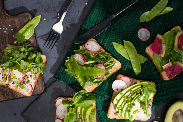 top view of vegetarian sandwiches with fresh vegetables on cloth and cutting boards with fork and knife - Foto, Imagem