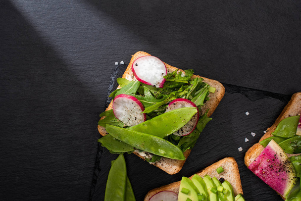 vrchní pohled na zdravé toasty s čerstvou zeleninou s pepřovými semínky a solí - Fotografie, Obrázek