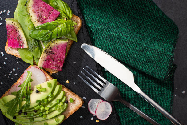 вид зверху на здорові бутерброди зі свіжими овочами на тканині з виделкою і ножем
 - Фото, зображення