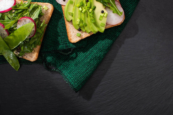 widok z góry wegetariańskie kanapki z rzodkiewką, porów i awokado na zielonym materiale - Zdjęcie, obraz